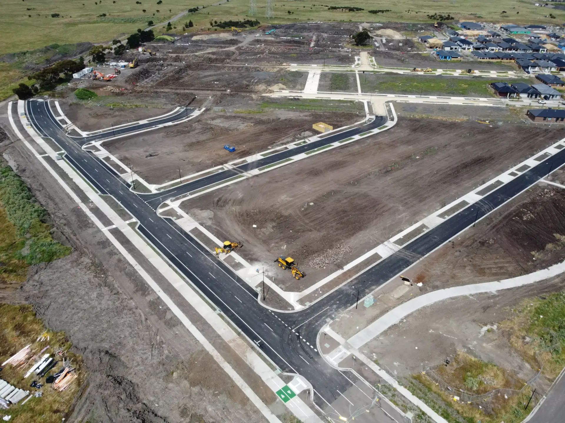 Aerial view of a Christchurch subdivision during construction. The roads are complete, concrete footpaths complete, transformer station complete, you can also see two yellow excavators in the dirt next to the Christchurch Quantity Surveyor.